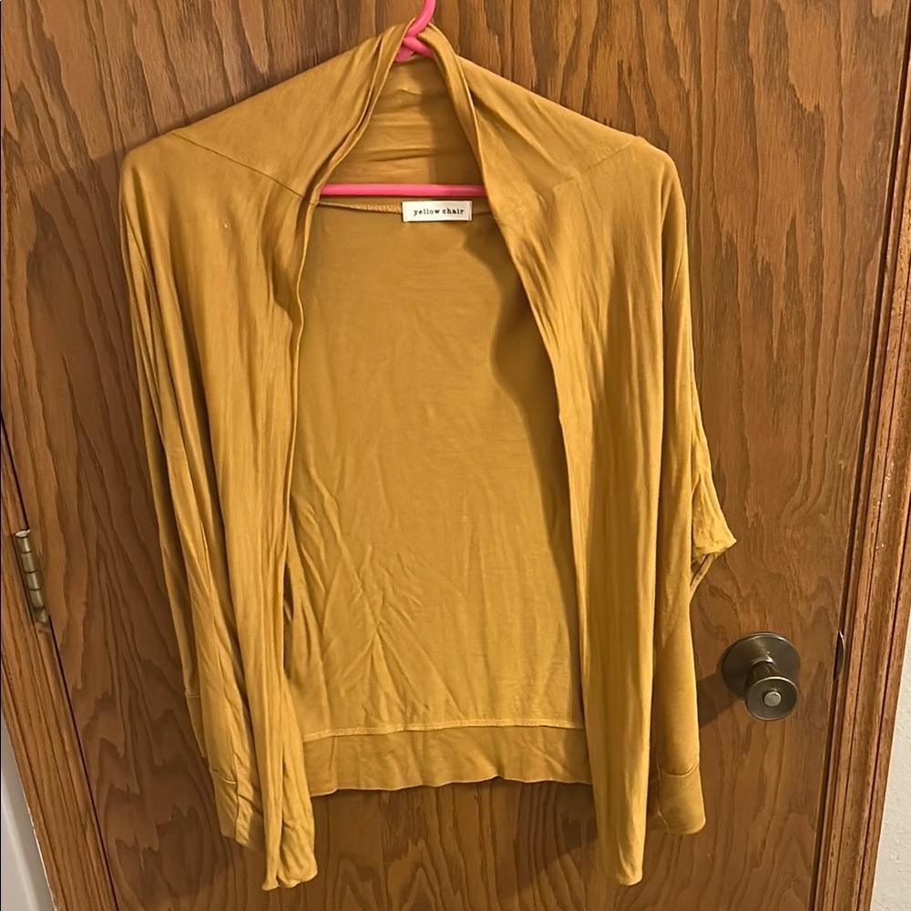 Medium women’s gold cardigan. Yellow chair